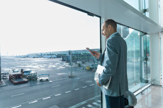 Passenger checks smartphone near window at Barcelona airport