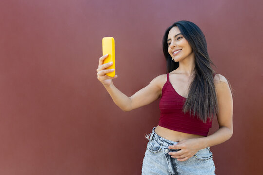 Smiling woman takes a selfie with a smartphone outdoors