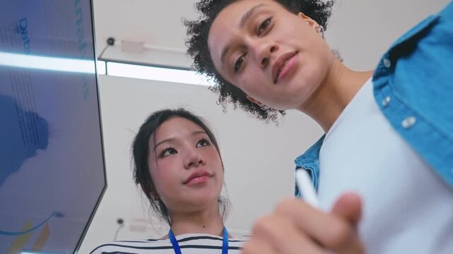 Asian and Brazilian Businesswomen Discussing Data Analysis with Tablet in Modern Office.