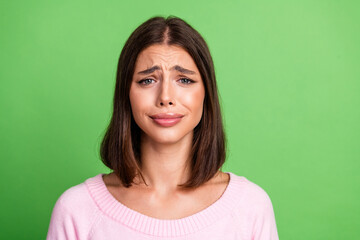 Fototapeta premium Young woman in pink sweater with a worried expression stands green background fashion style and everyday mood for advertising lifestyle beauty and promo projects