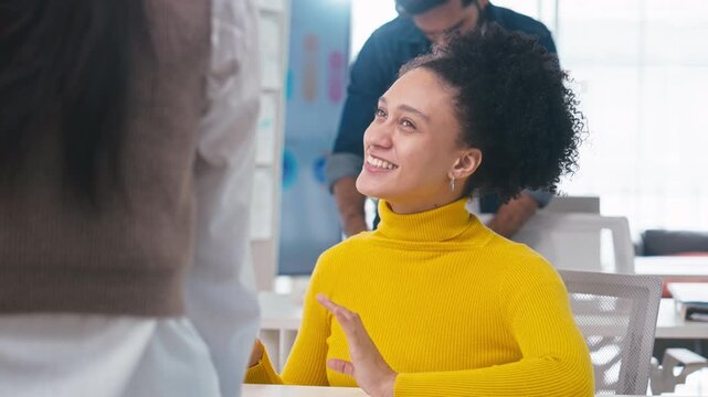 Slow motion Cheerful professional businesswoman in a yellow sweater talking and gesturing during a team meeting in a modern corporate office setting.