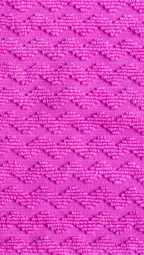 Pink fabric texture with chevron pattern, raised zig zag embroidery details on woven textile background