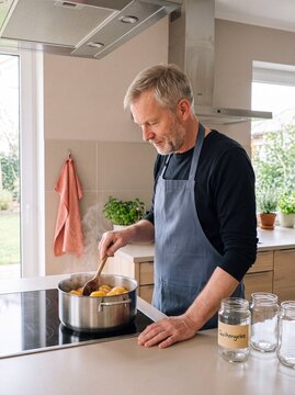 &Auml;lterer Mann kocht Quitten im Topf zum Einkochen von Quittengelee