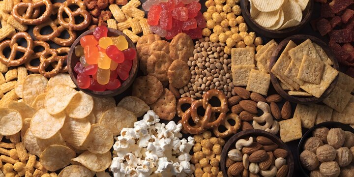 Assorted crunchy snack mix with pretzels, crackers, nuts and savory bites, rich textured food background