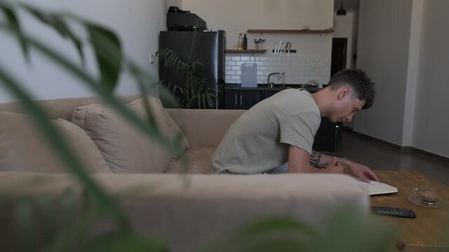 Personal planning and everyday life organization at home, man reviews handwritten notes, takes a coffee break and uses smartphone while managing routine tasks in a candid lifestyle scene