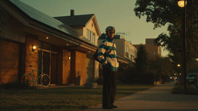 Cyclist on Suburban Street near Homes with Solar Panels