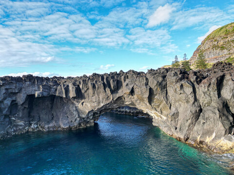 Natural volcanic rock arch at A Porta do Diabo on the rugged coast near Ponta da Ferraria, S&atilde;o Miguel Island, Azores, Portugal, surrounded by clear Atlantic Ocean water