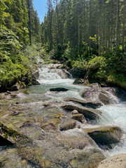 Obraz premium Scenic Mountain Stream Flowing Through Forest in Königsleiten Austria Tirol on a Sunny Summer Day With Rocks and Greenery Perfect for Travel and Tourism