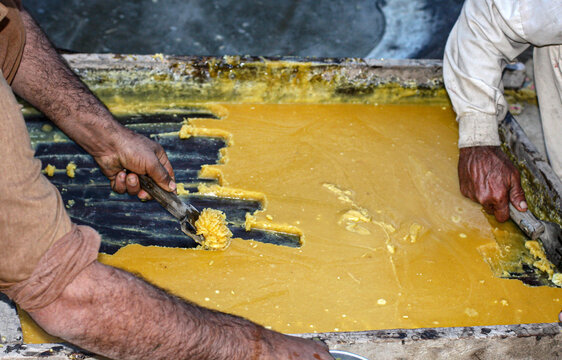 View of workers processing traditional jaggery in a large tray in Multan, Punjab, Pakistan.