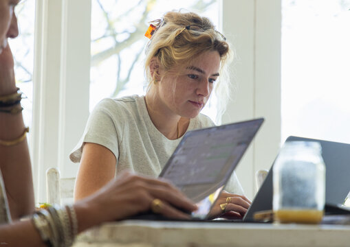young woman working on laptop in light filled room