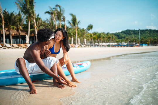 Happy young couple embracing and laughing on a tropical beach during summer vacation