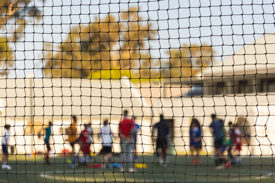 abstract view of soccer players out of focus from behind soccer net