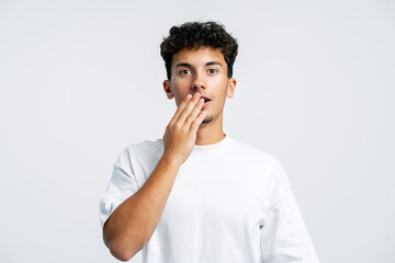 Young man covering mouth expressing surprise disbelief