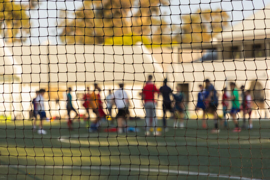 abstract view of soccer players out of focus from behind soccer net
