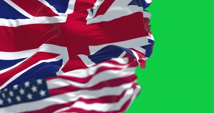 UK and US national flags waving in the wind isolated on green background