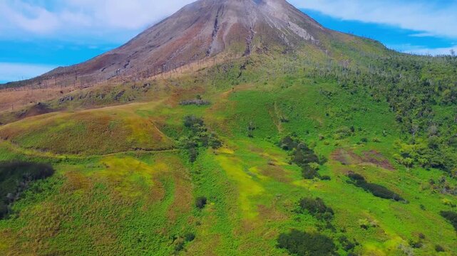 Aerial view of Mount Sinabung with lush green slopes and volcanic terrain in Naman Teran, North Sumatra, Indonesia.