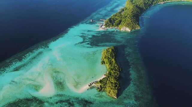 Aerial view of Raja Ampat Regency featuring lush tropical islands surrounded by vibrant turquoise coral reefs and deep blue ocean waters in Kri Island, Southwest Papua, Indonesia.