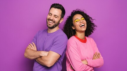Obraz premium Happy young couple standing back-to-back laughing with arms crossed against a vibrant purple background.