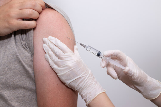 Doctor giving vaccine injection into patient's shoulder during preventive medical procedure. Concept of measles vaccination, mumps vaccination, rubella vaccination, polio vaccination.
