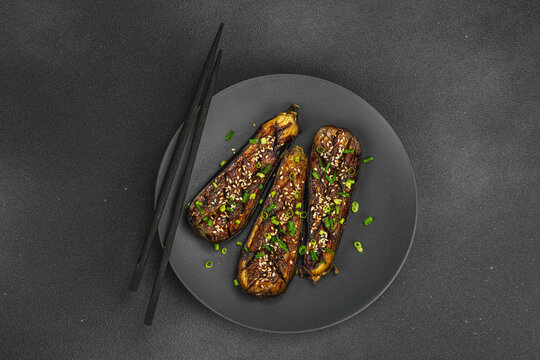 Miso glazed eggplant half with sesame seeds and green onion on a plate