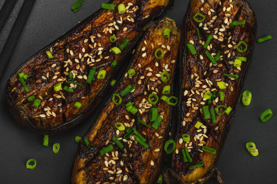 Miso glazed eggplant half with sesame seeds and green onion on a plate