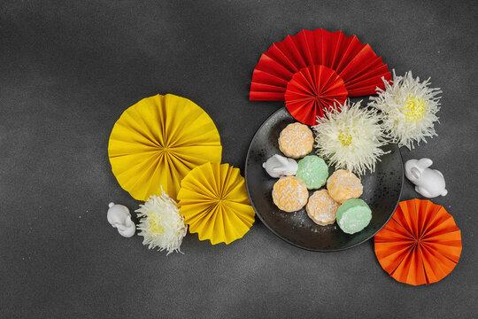 Traditional Chinese mooncakes on a plate with paper fans, ceramic rabbits, and chrysanthemums