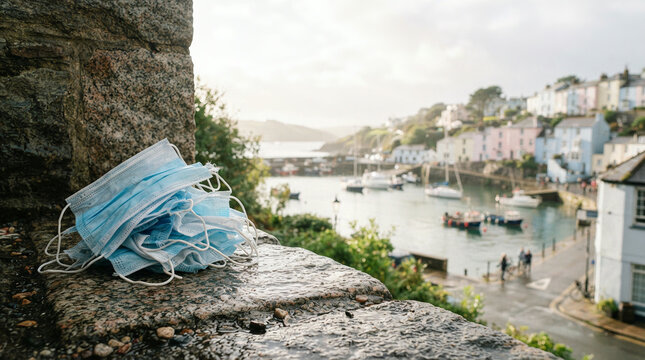 Stack of blue face masks on a granite ledge above a harbour town outdoors