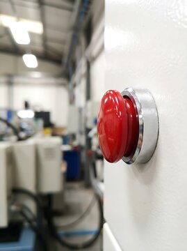 Red emergency stop button pressed in industrial setting