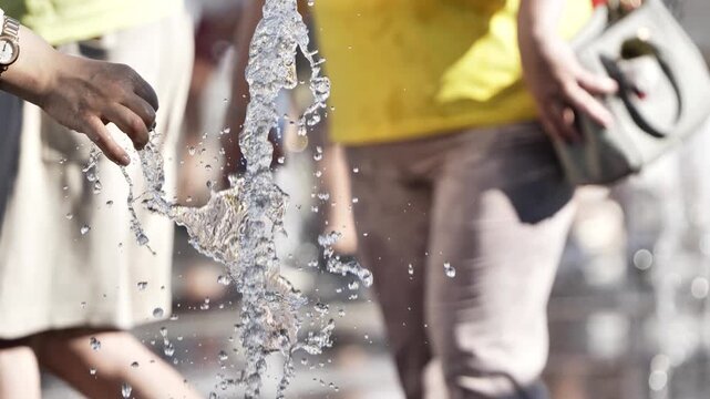 Hand playing with water from a fountain, cooling off in summer heat