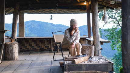 Obraz premium A woman drinking coffee on wooden terrace and looking at nature views