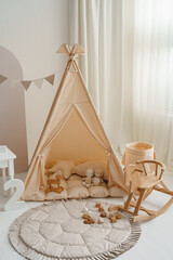 Neutral beige kids studio interior with wigwam tent, ONE blocks and rocking horse for birthday © Minakryn Ruslan 