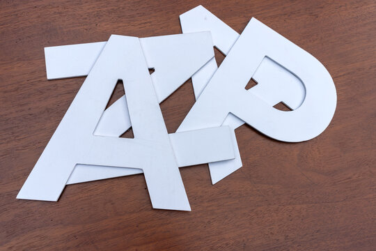 White plastic alphabet letters scattered on wooden table. Cut out letters for education, typography and spelling concept. Learning alphabet and language study background