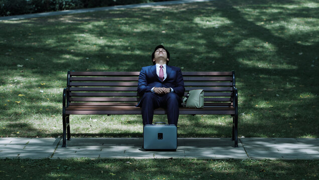 公園のベンチで仮眠する会社員