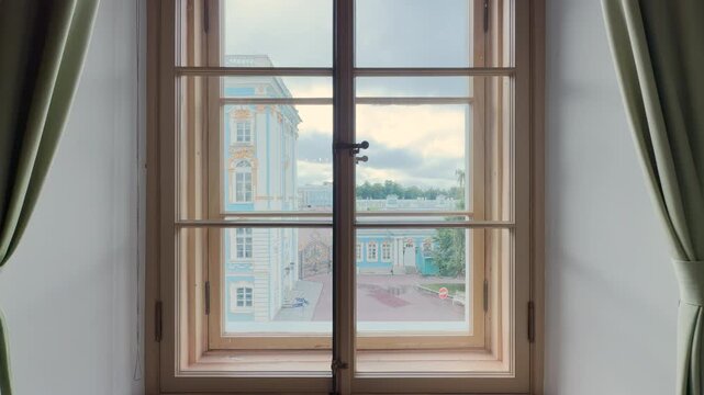A wooden window frames the view of Catherine Palace in Pushkin, Saint Petersburg. The bright landscape brings a peaceful feeling of nostalgic wonder.