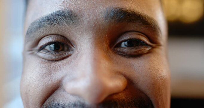 Face is smiling and blinking into camera at cafe booth as eye contact is initiating warmth