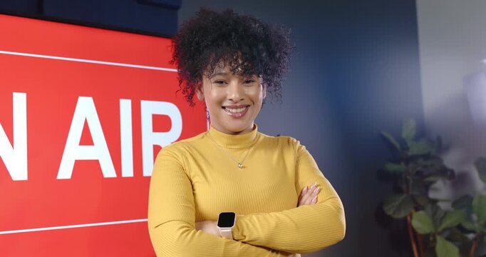 Camera reframing and zooming adult African woman posing arms crossed hosting, smiling on AIR set