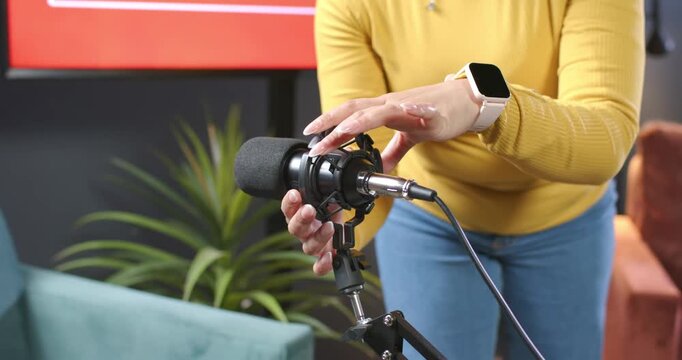 Presenter is stepping forward and adjusting shock mount to align microphone for recording in studio
