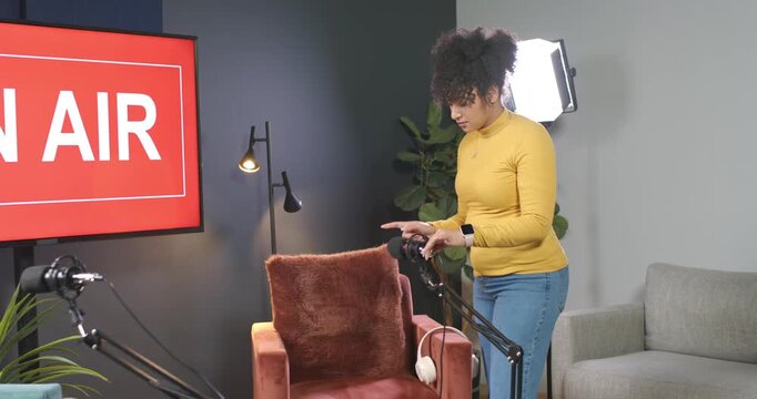 Set African American woman in mustard top tuning mic boom, moving white headphones after AIR cue
