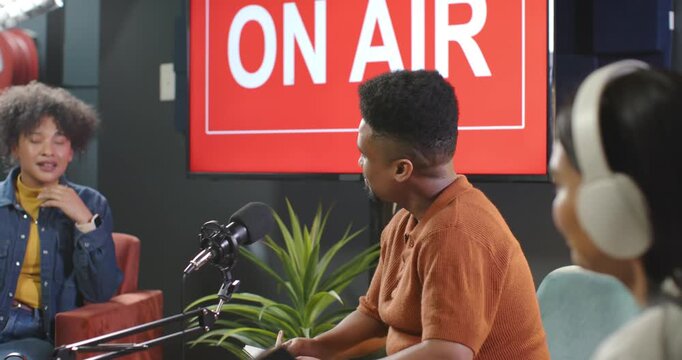 African podcast hosts and guest interviewing, camera panning, host jotting notes