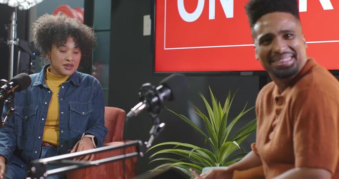 African American hosts laughing, intro sparking chat while filming on set with mics, red monitor