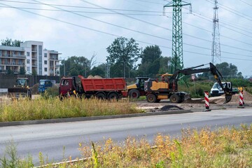 Heavy Construction Machinery at Urban Roadworks Beneath High Voltage Power Lines © Margarita