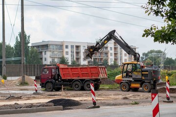 Excavator Loading Dump Truck at Active Urban Road Construction Site © Margarita