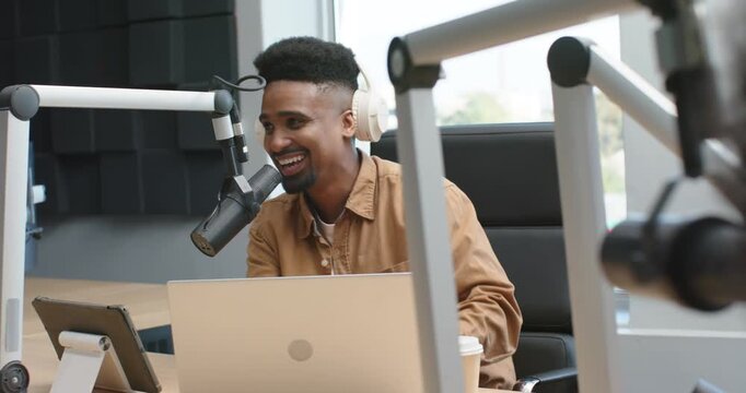 African American man reacting to co-host comment, leaning into mic, speaking at desk with laptop