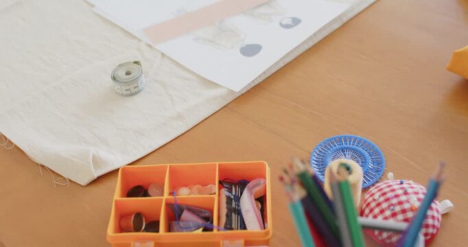 Camera is tilting upward revealing orange organizer and notions on table to show workspace