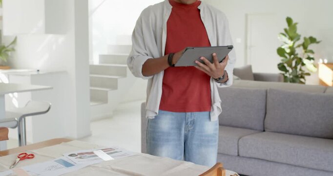 African American man noticing patterns on wood table stepping and tapping tablet for sewing at home