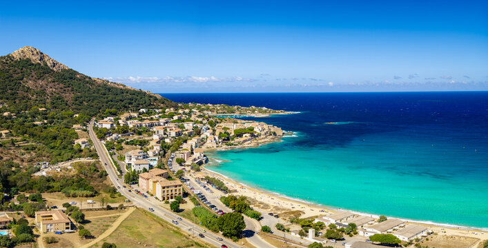 Algajola Corsica France aerial drone camera tilt down turquoise emerald sea golden sand beach resort town Balagne Ile Rousse region summer travel destination