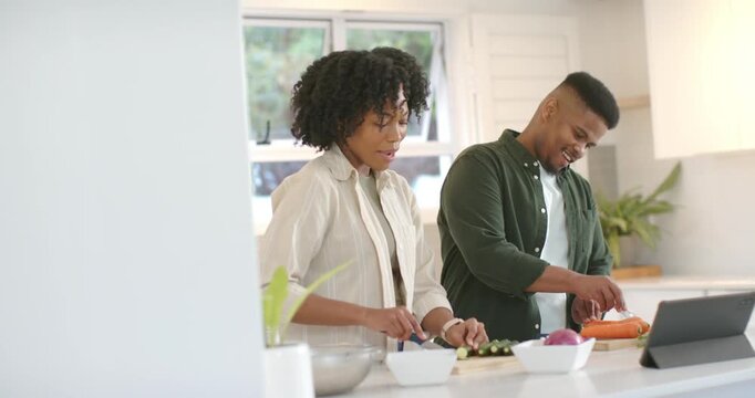 African American couple chopping boards in kitchen, using tablet recipe, preparing meal, copy space
