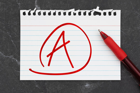 Grade A with circle on a white lined torn paper with pen on black stone