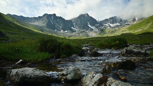 Mountain stream flowing over rocks in alpine valley
