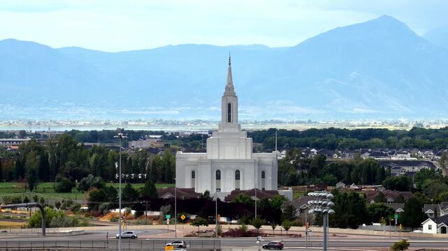 Orem, Utah, United States - 30 August 2026: Aerial view of the Orem Utah Temple surrounded by residential neighborhoods and lush trees with mountains in the background.